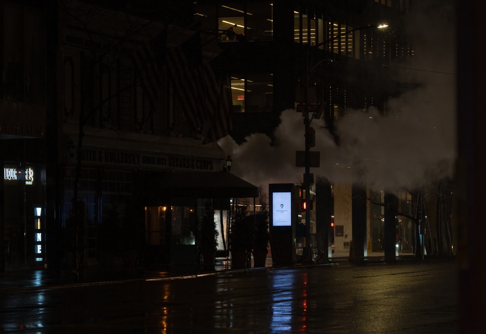 a city street at night with steam coming out of a building