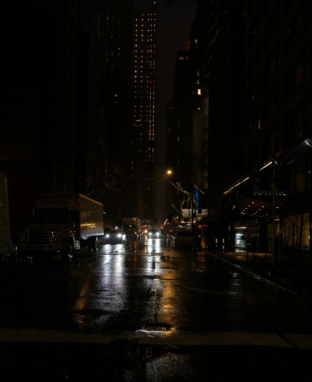 a city street at night with cars parked on the side of the road