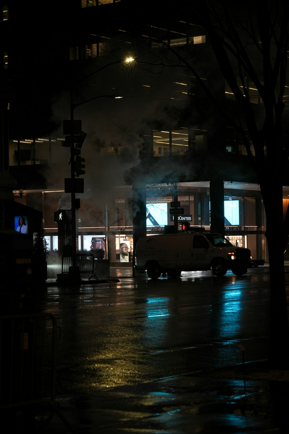 a dark city street at night with a van parked on the side of the road