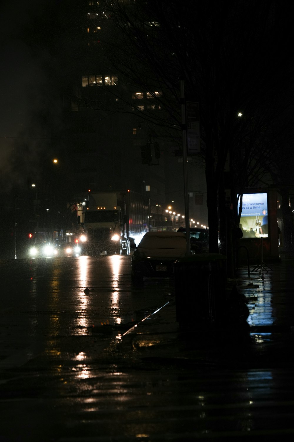 a city street at night with cars driving on it