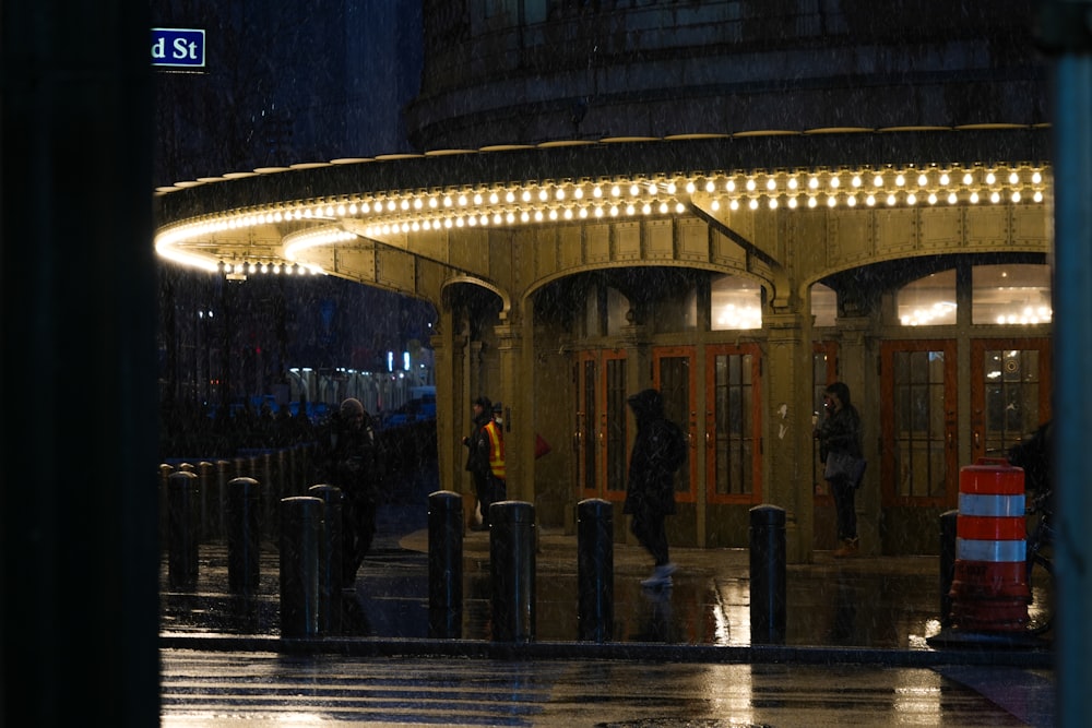 a group of people standing outside of a building at night