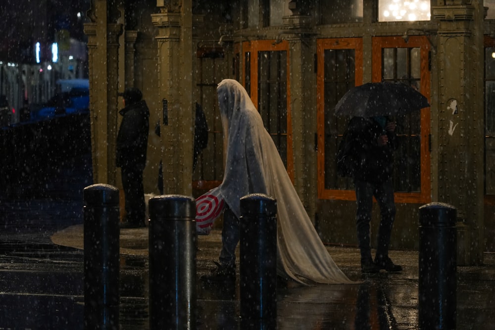a bride and groom stand under an umbrella in the rain