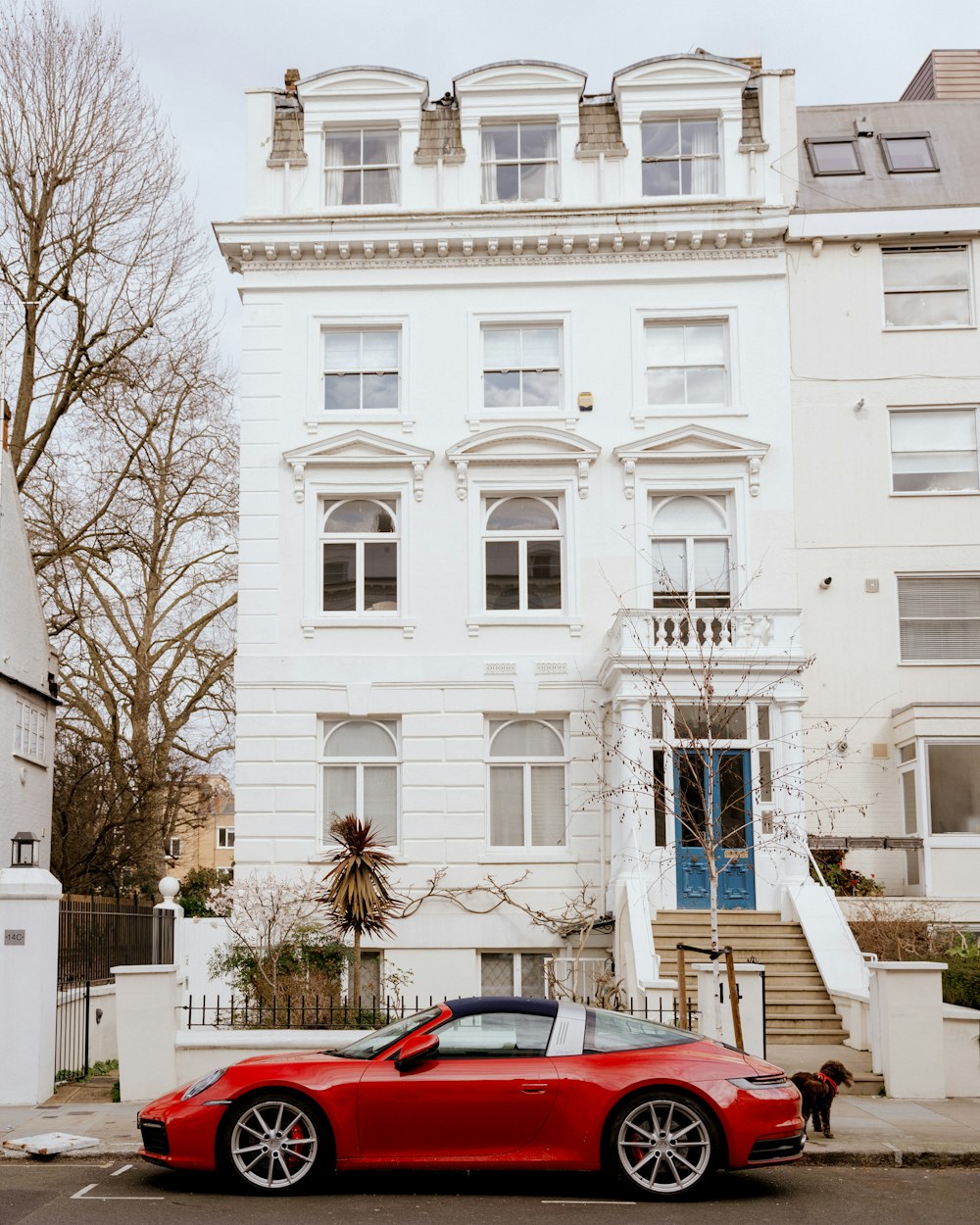 Un coche deportivo rojo aparcado frente a un edificio blanco