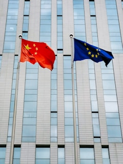 two flags flying next to each other in front of a building