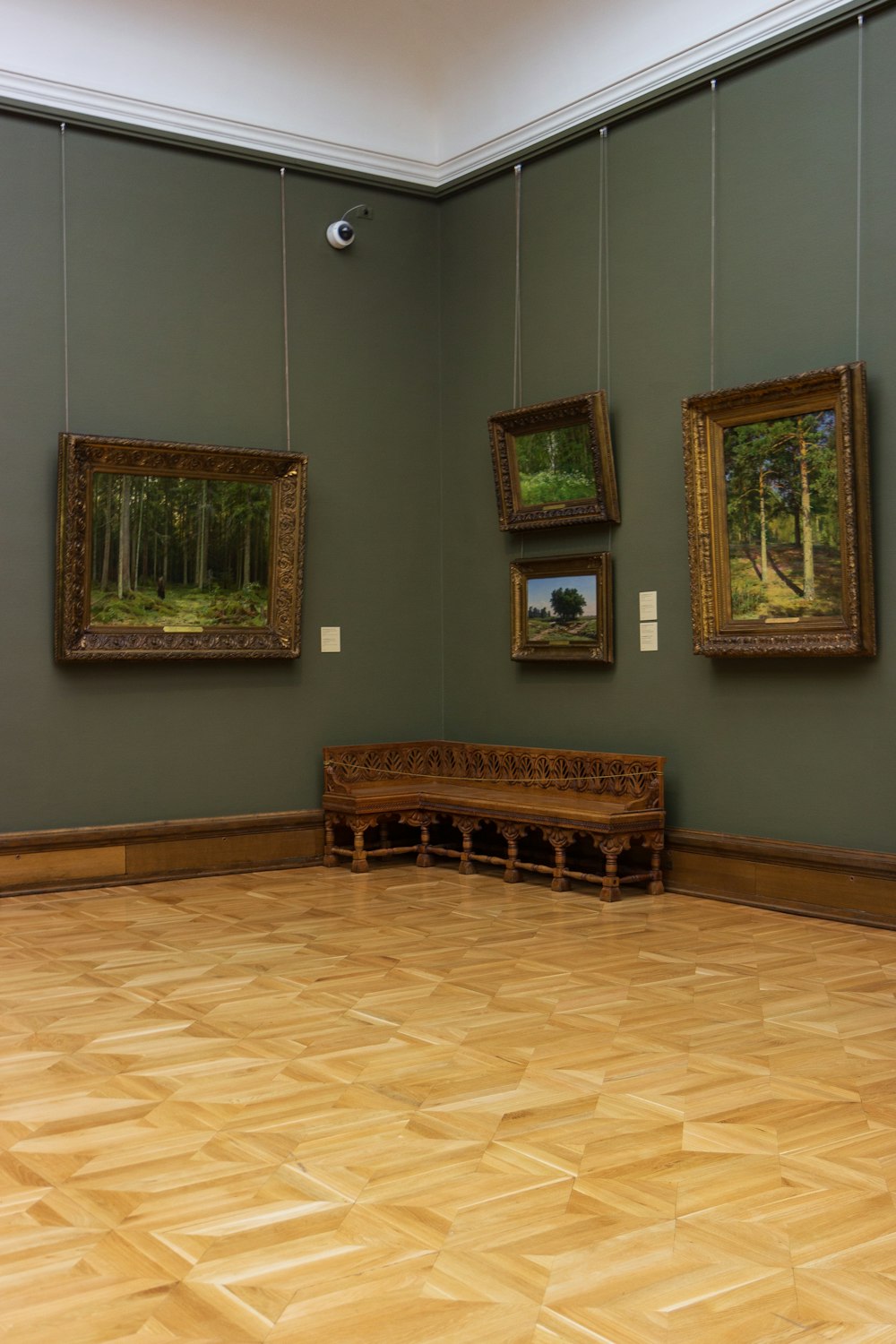 a room with a wooden floor and paintings on the wall