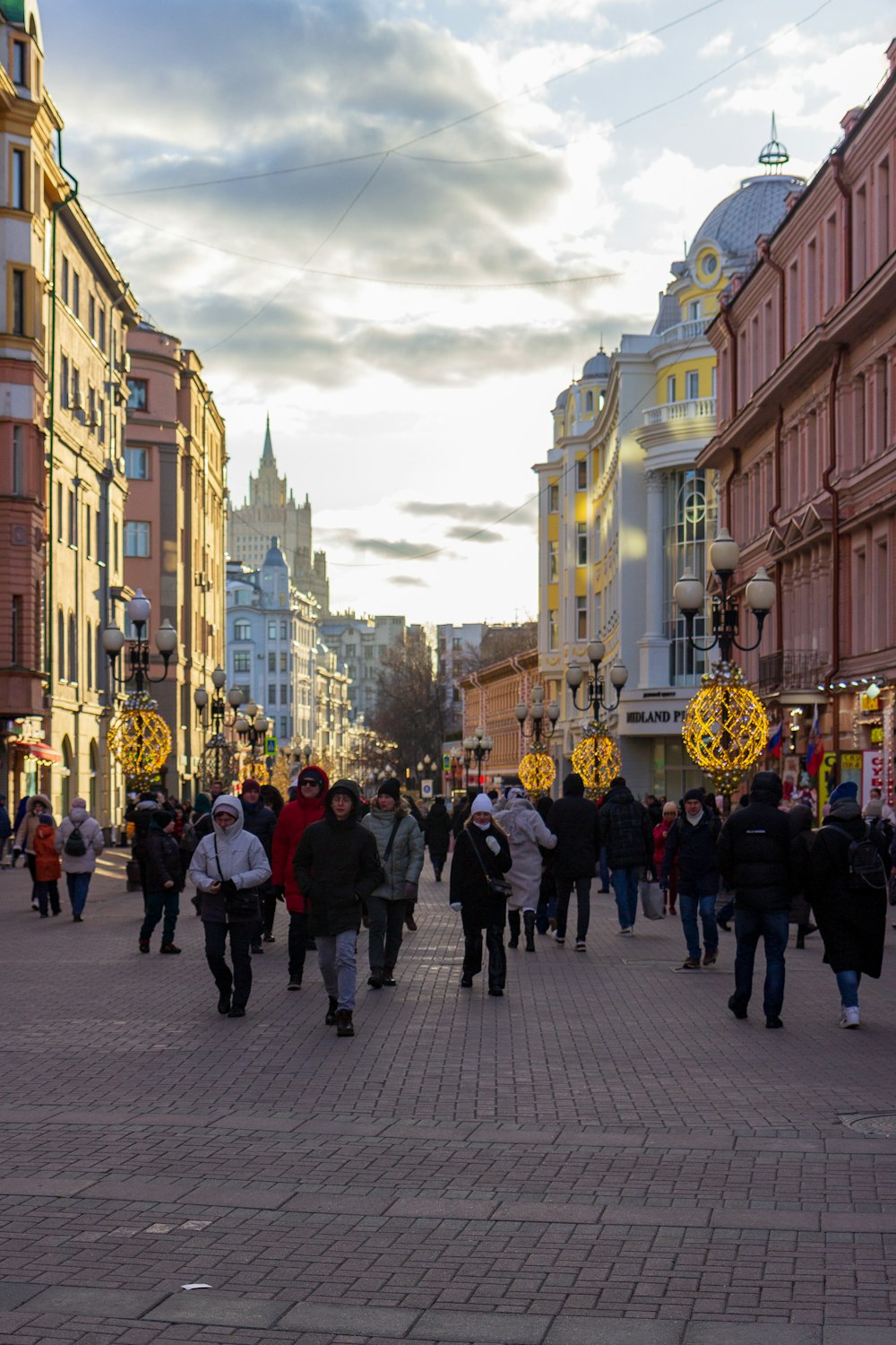 a group of people walking down a street next to tall buildings