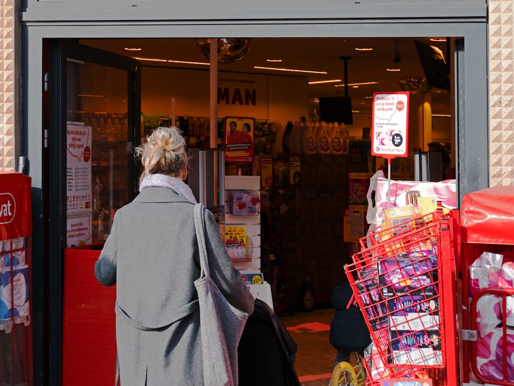 a woman walking out of a store with a shopping cart