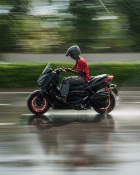 a man riding a motorcycle down a rain soaked street
