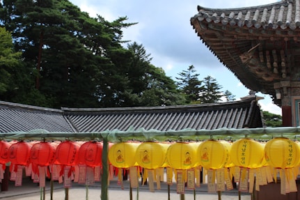 a row of yellow and red lanterns in front of a building