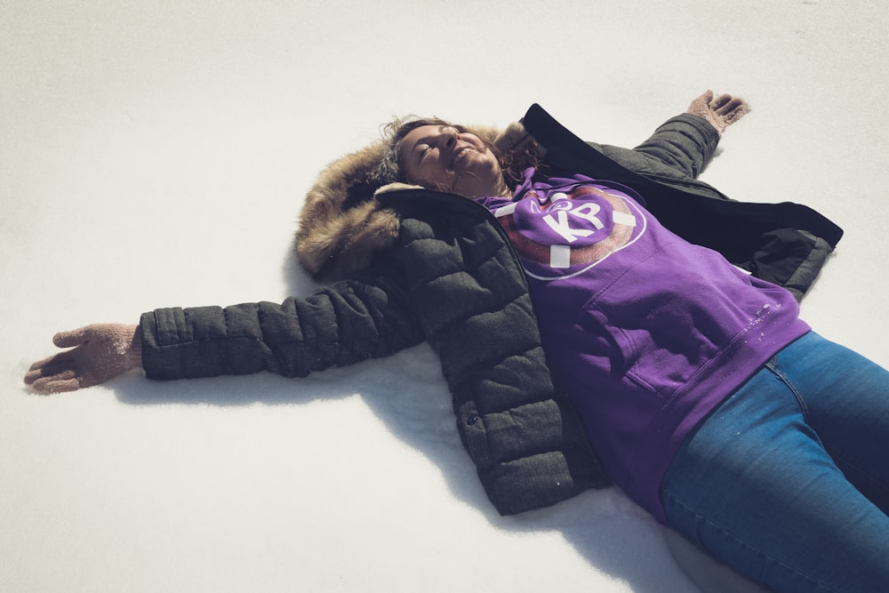 a woman laying on the ground wearing a purple shirt