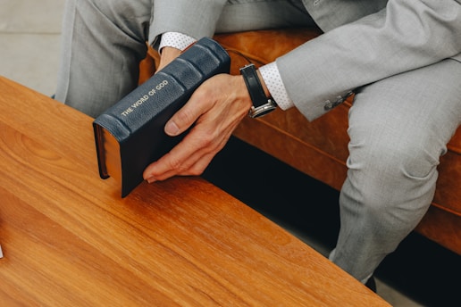 A man in a suit sitting at a table with a book