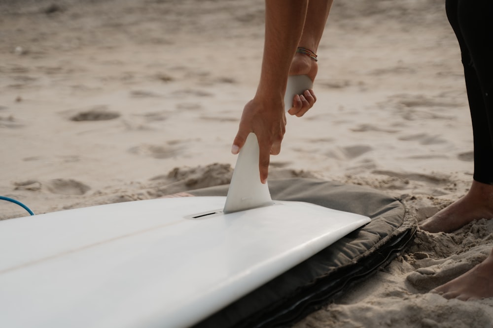 a person sanding next to a surfboard on the beach