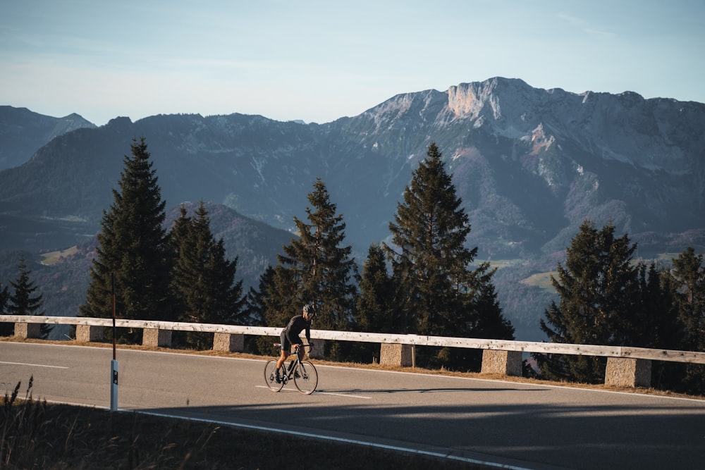 a person riding a bike on a road with mountains in the background