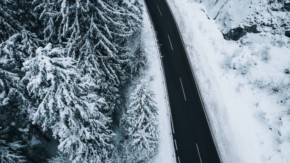 an aerial view of a road surrounded by snow covered trees