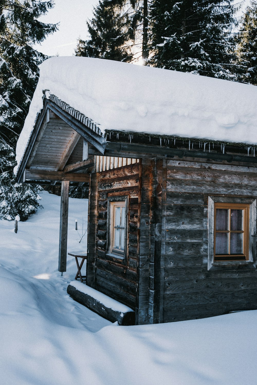 a log cabin in the snow with snow on the roof