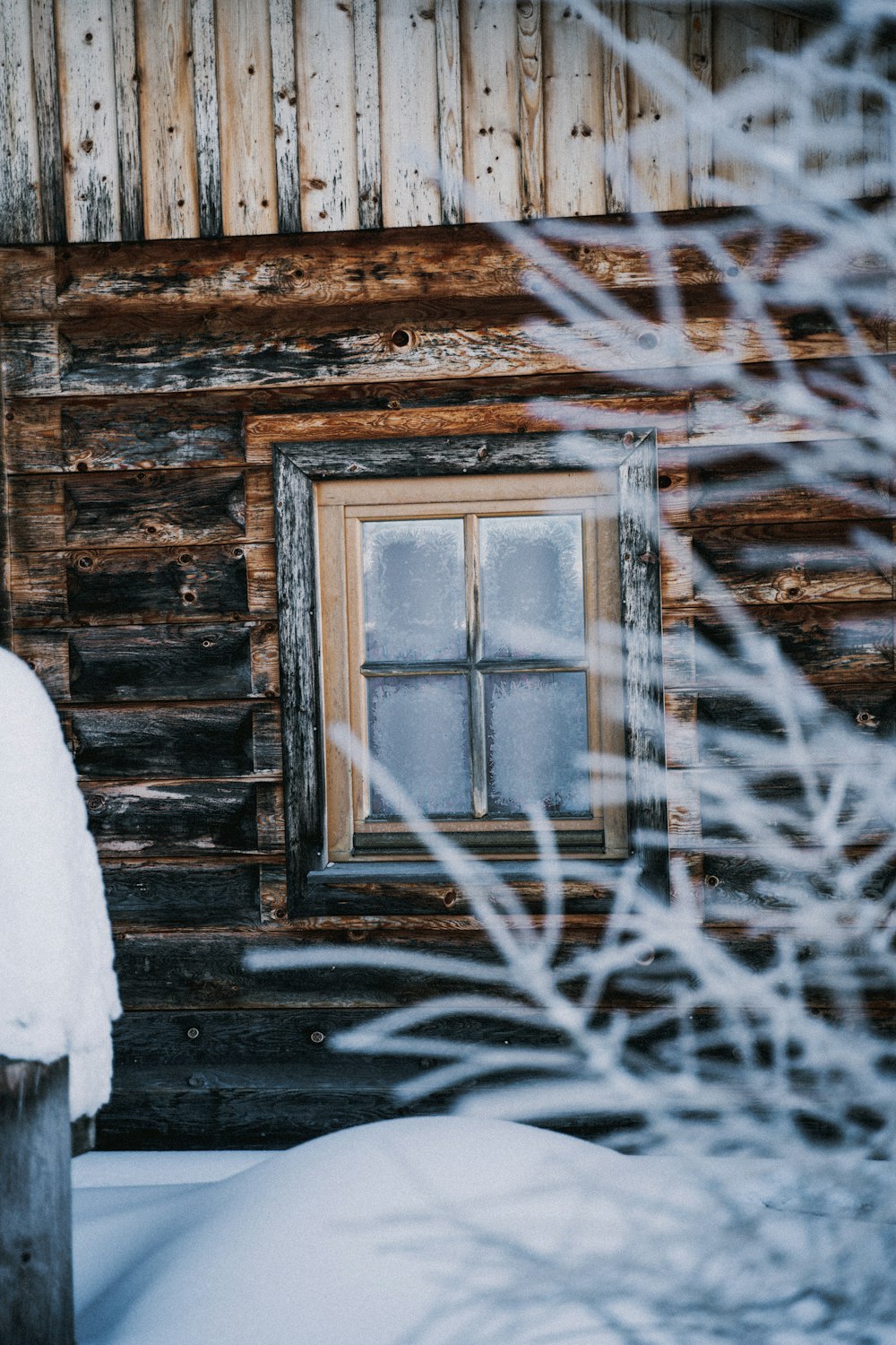 a log cabin with snow on the ground and a window
