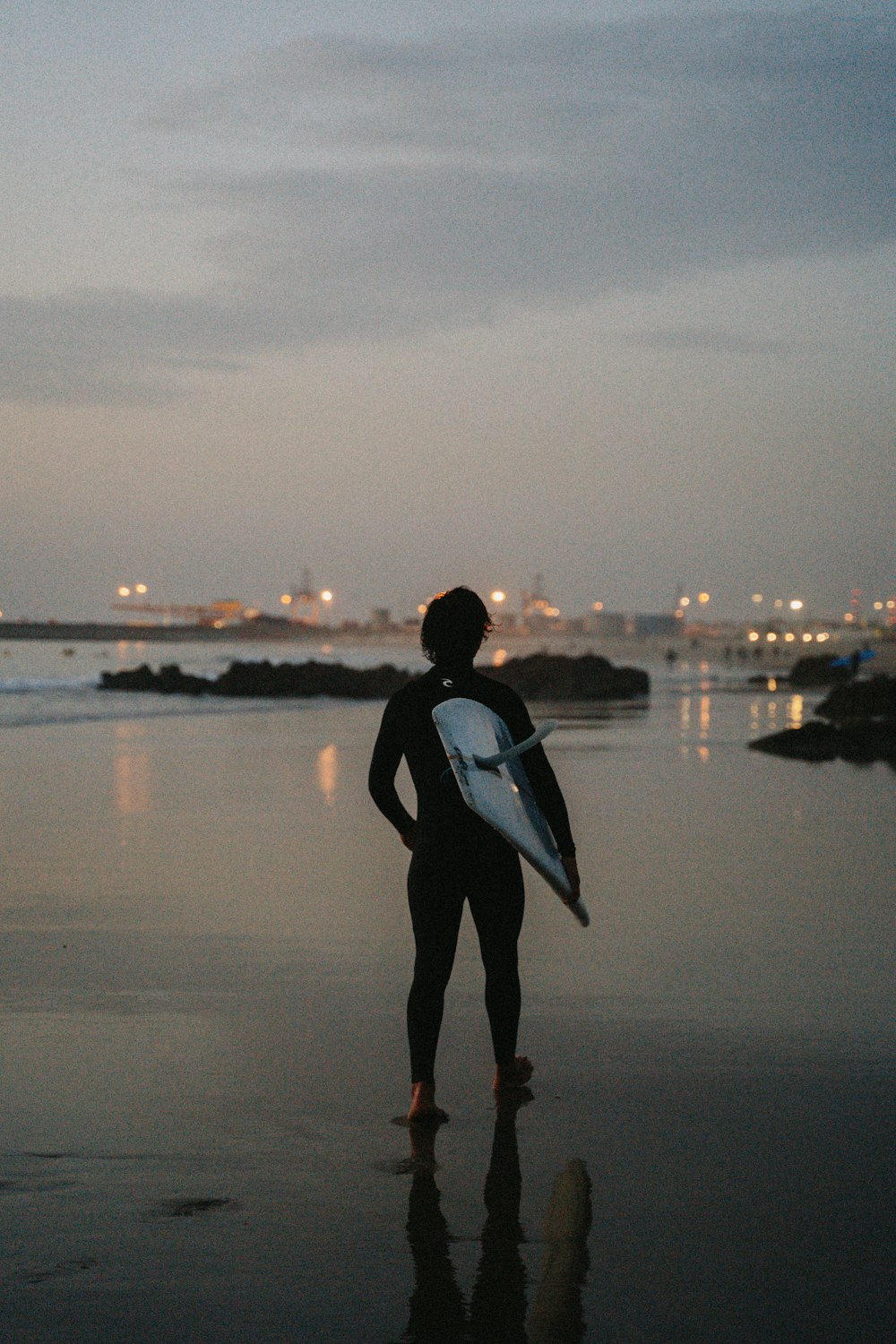 una persona in piedi su una spiaggia con in mano una tavola da surf