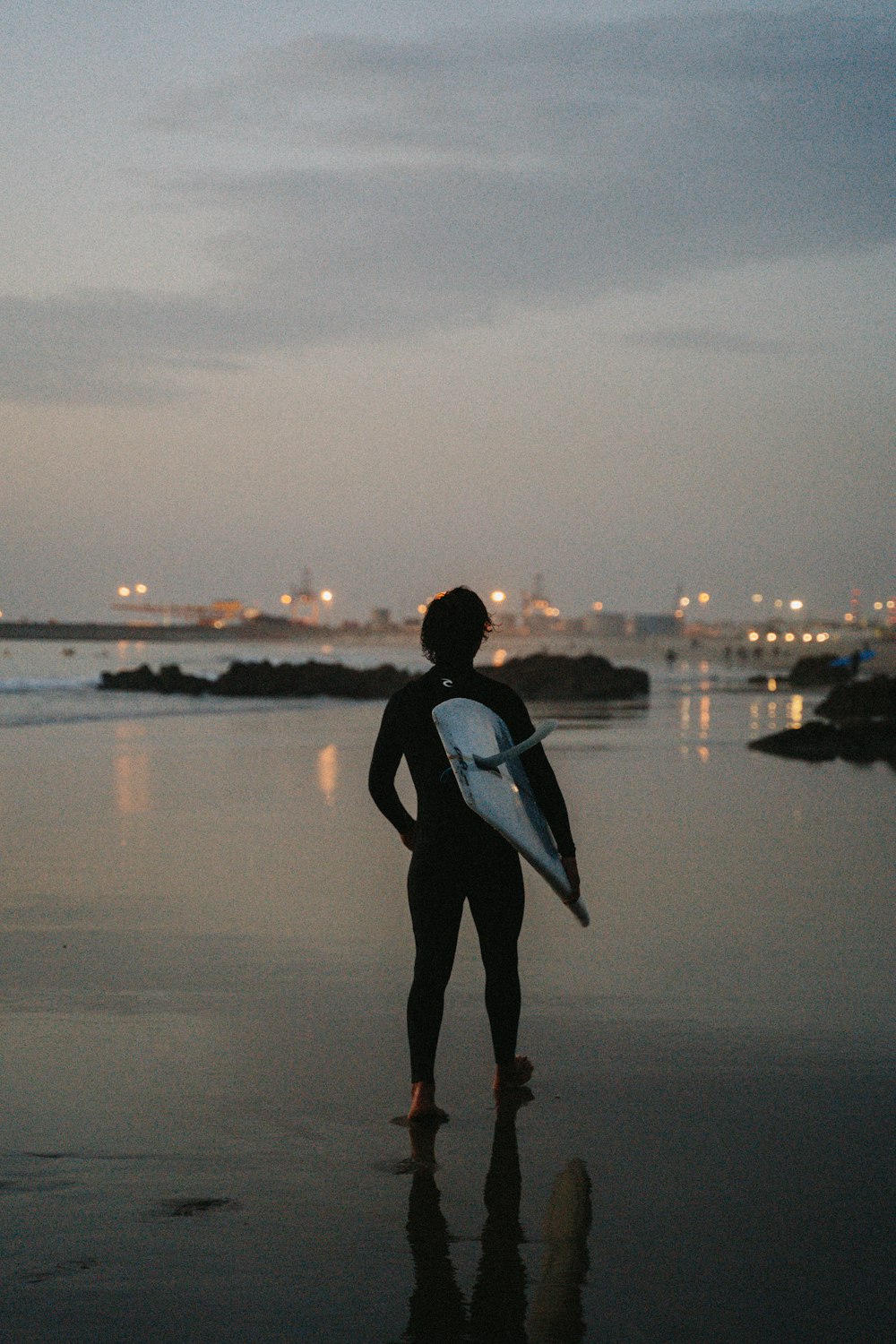 a person standing on a beach holding a surfboard