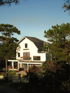 a white house surrounded by trees on a sunny day