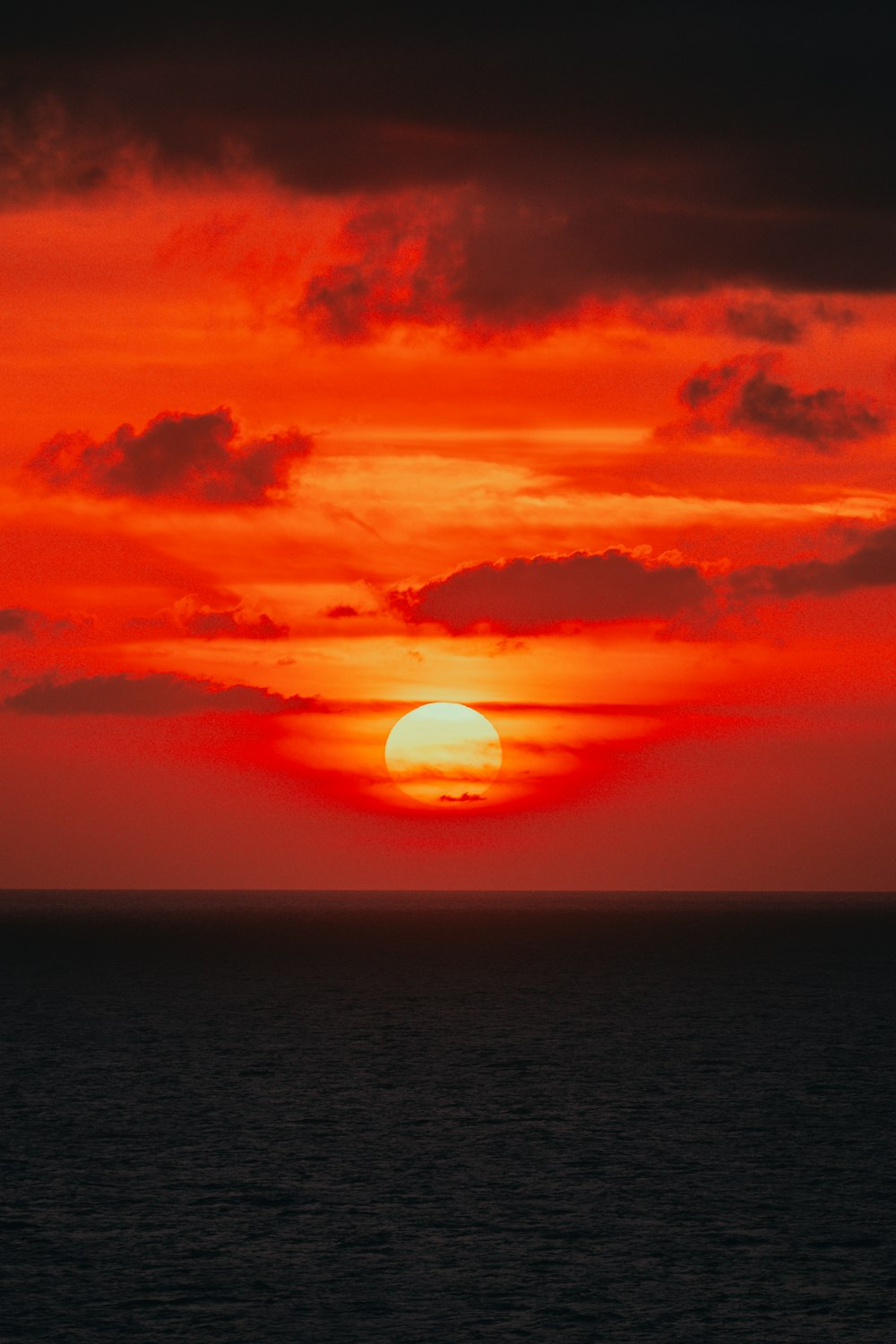 the sun is setting over the ocean on a cloudy day