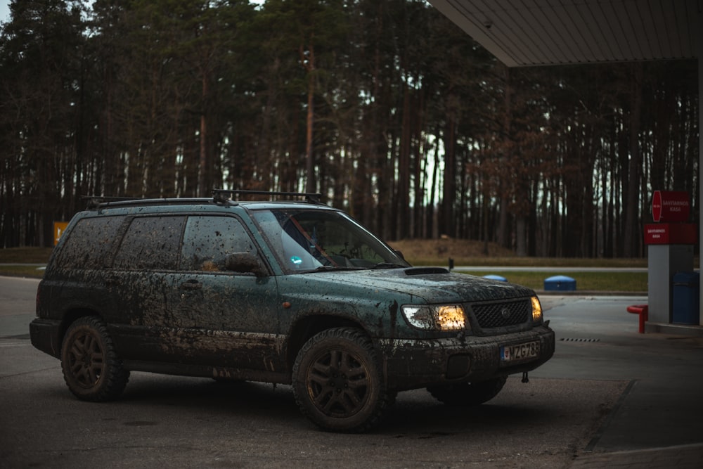 a dirty suv parked in front of a gas station