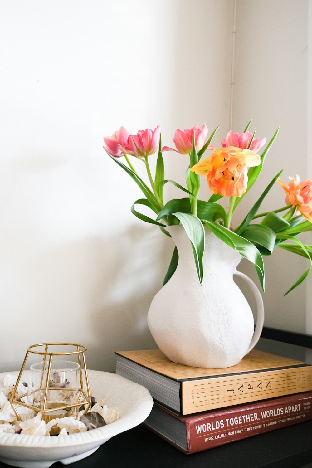 a white vase filled with pink and orange flowers