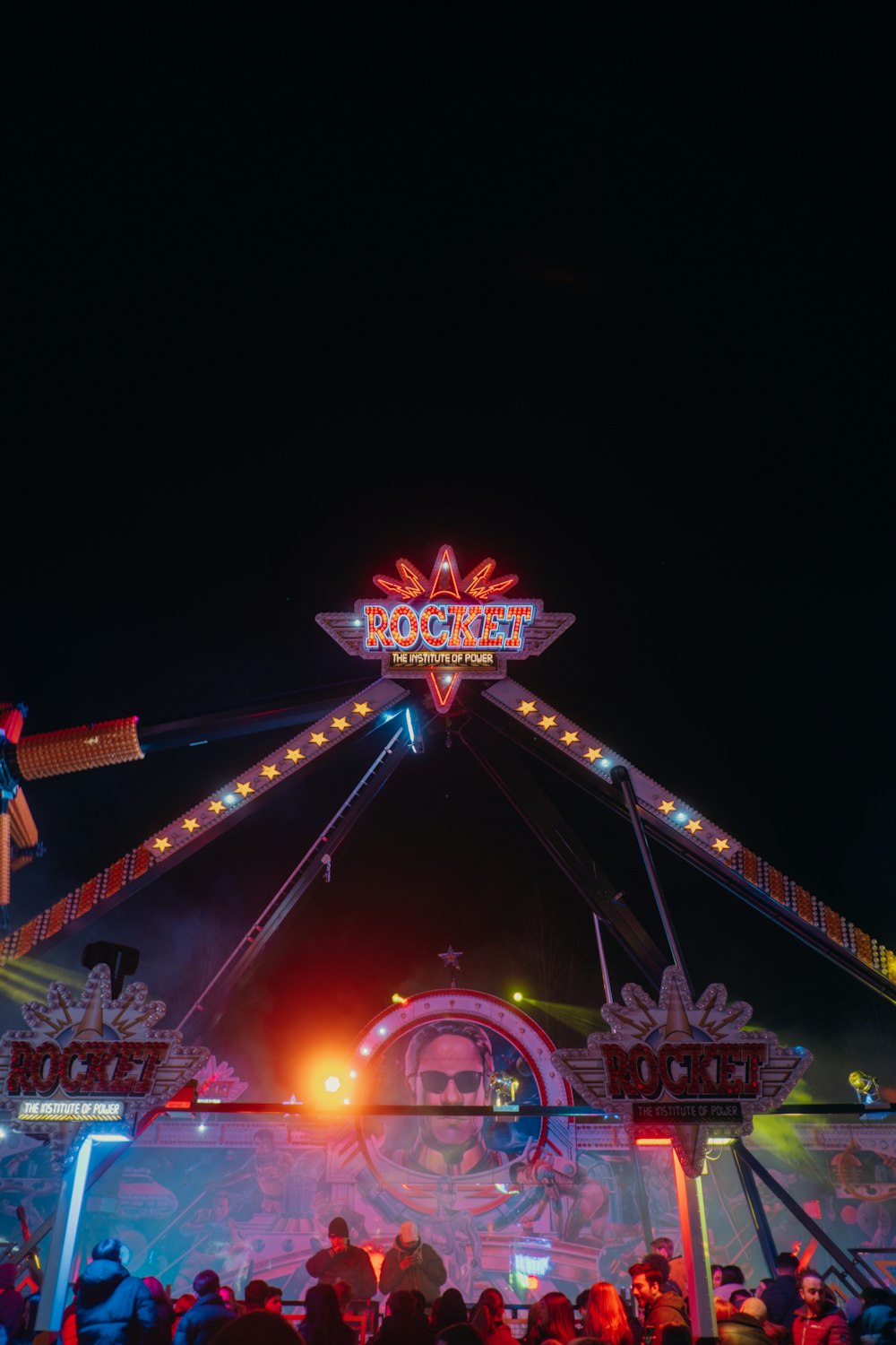 a carnival ride at night with people standing around