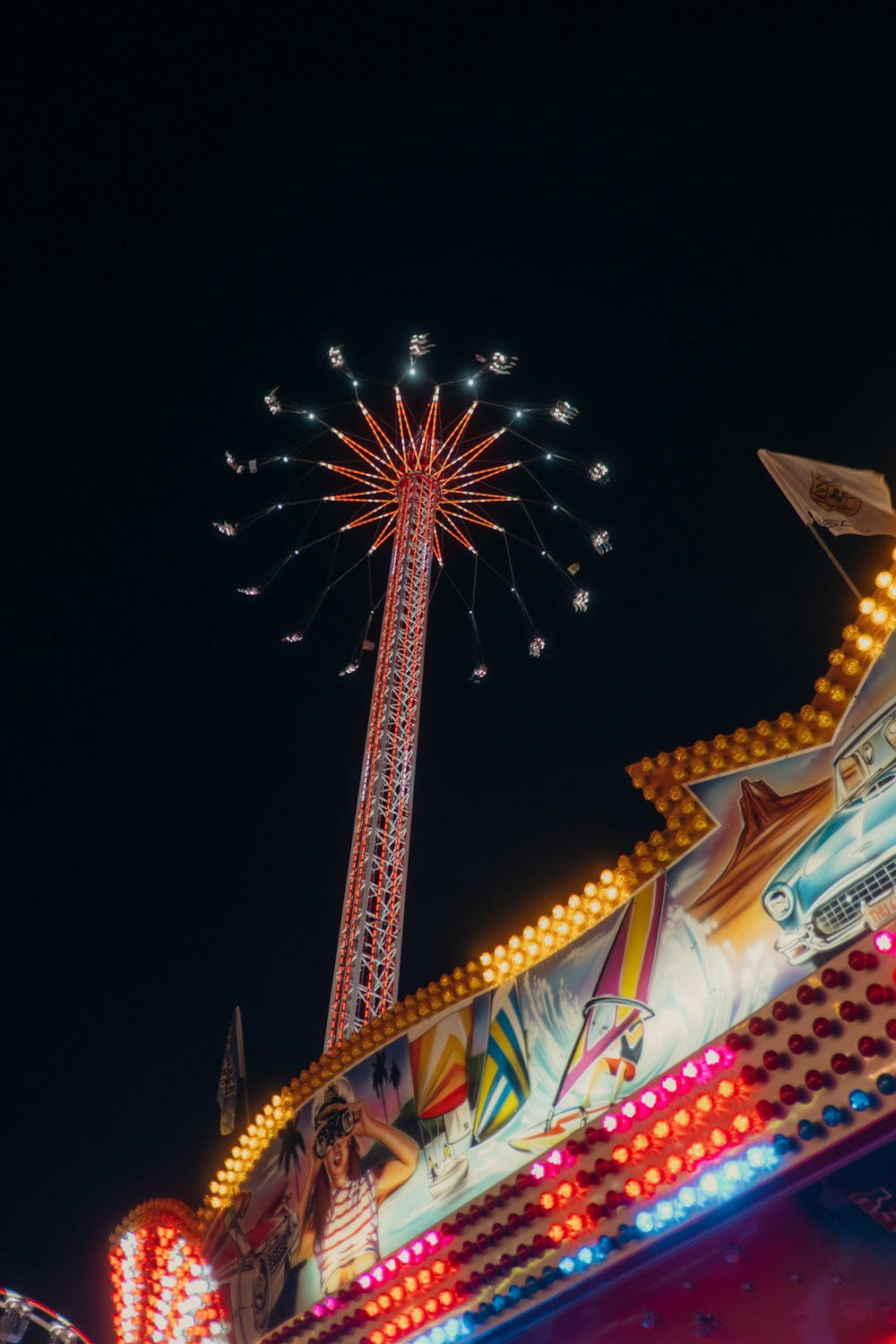 a carnival ride at night with a ferris wheel in the background