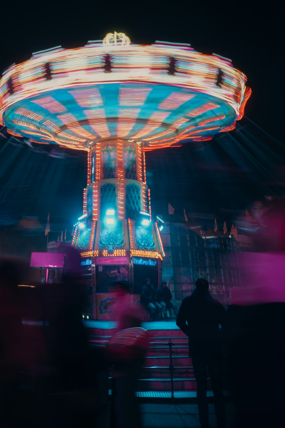 Un paseo de carnaval por la noche con gente de pie alrededor