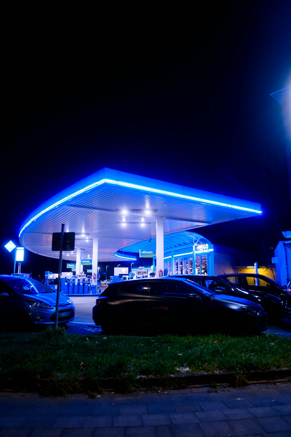 a gas station lit up at night with cars parked