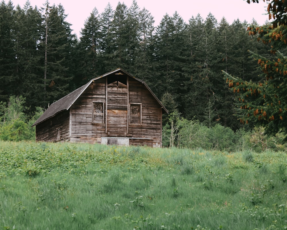 an old barn in a field with trees in the background