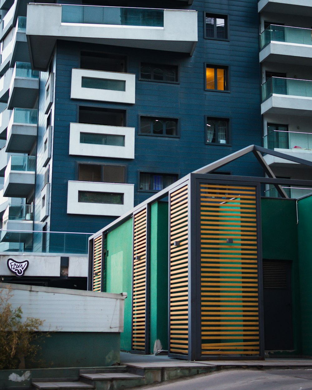 a tall building with a green door next to a street