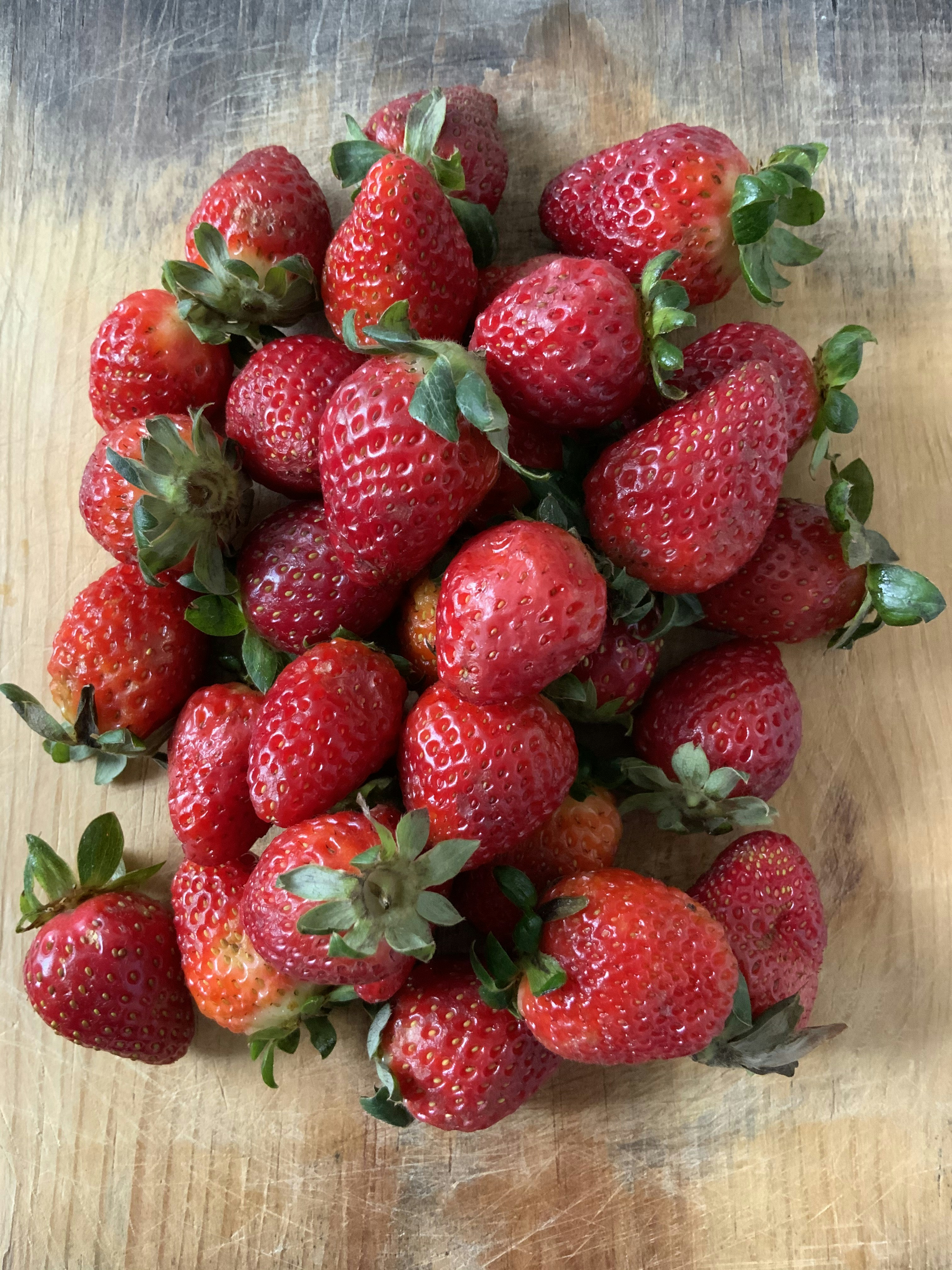 Bright red ripe strawberries scattered on a wooden surface in warm sunlight
