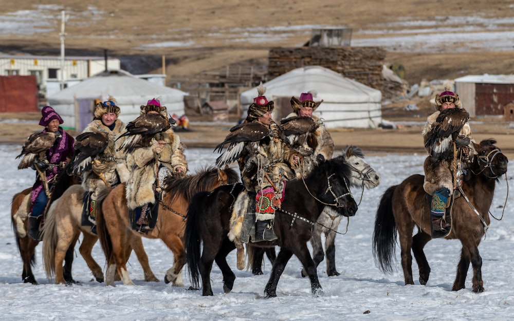 a group of people riding horses in the snow