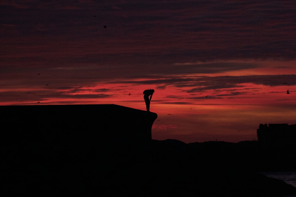 a person standing on the edge of a cliff at sunset