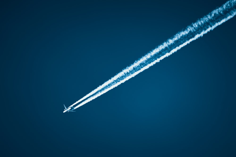 a jet flying in the sky leaving a trail of smoke