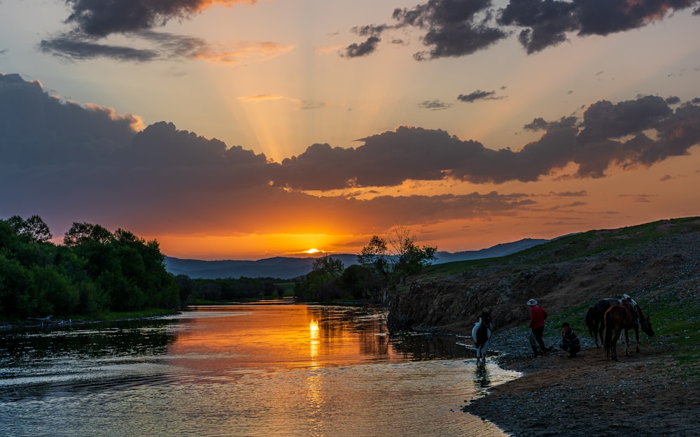 a group of people riding horses across a river