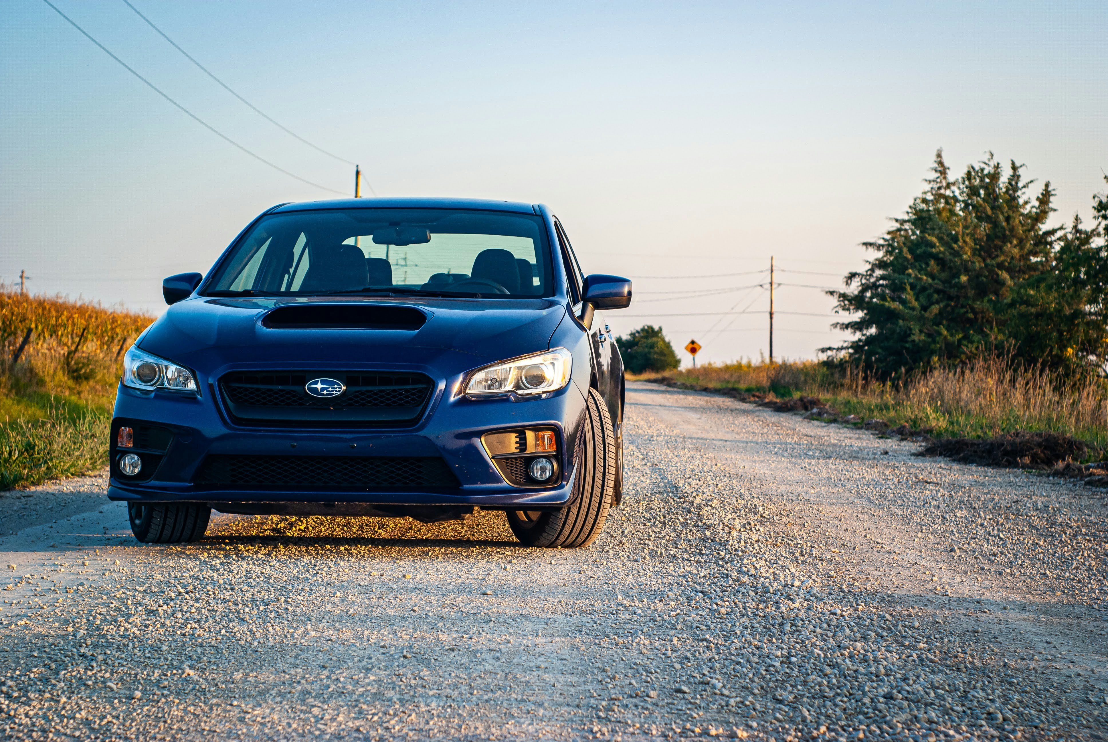 a blue subarunt is parked on a gravel road