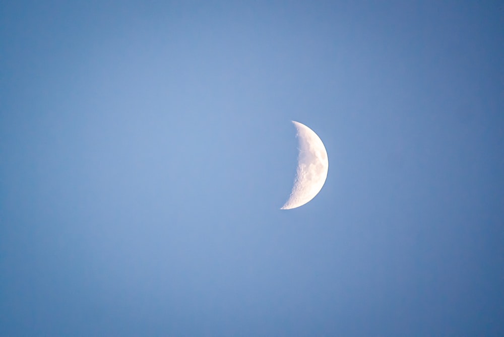 a half moon in a clear blue sky