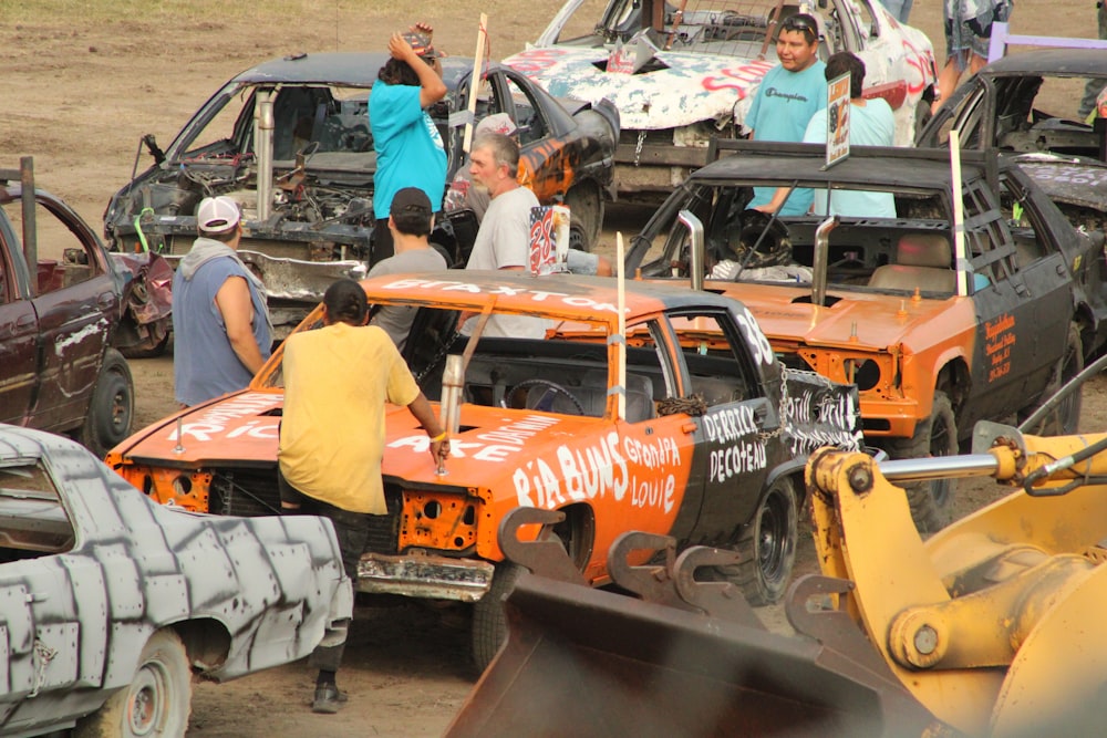 a group of people working on a car in a dirt lot