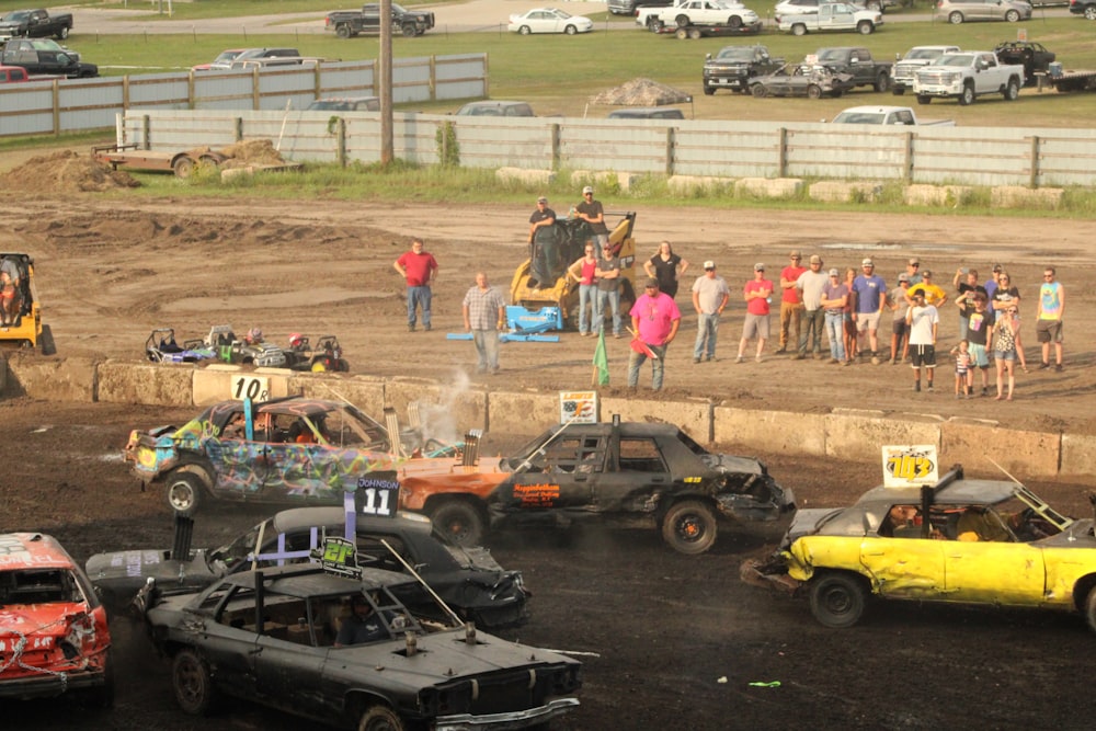 a group of people watching a group of cars on a dirt track