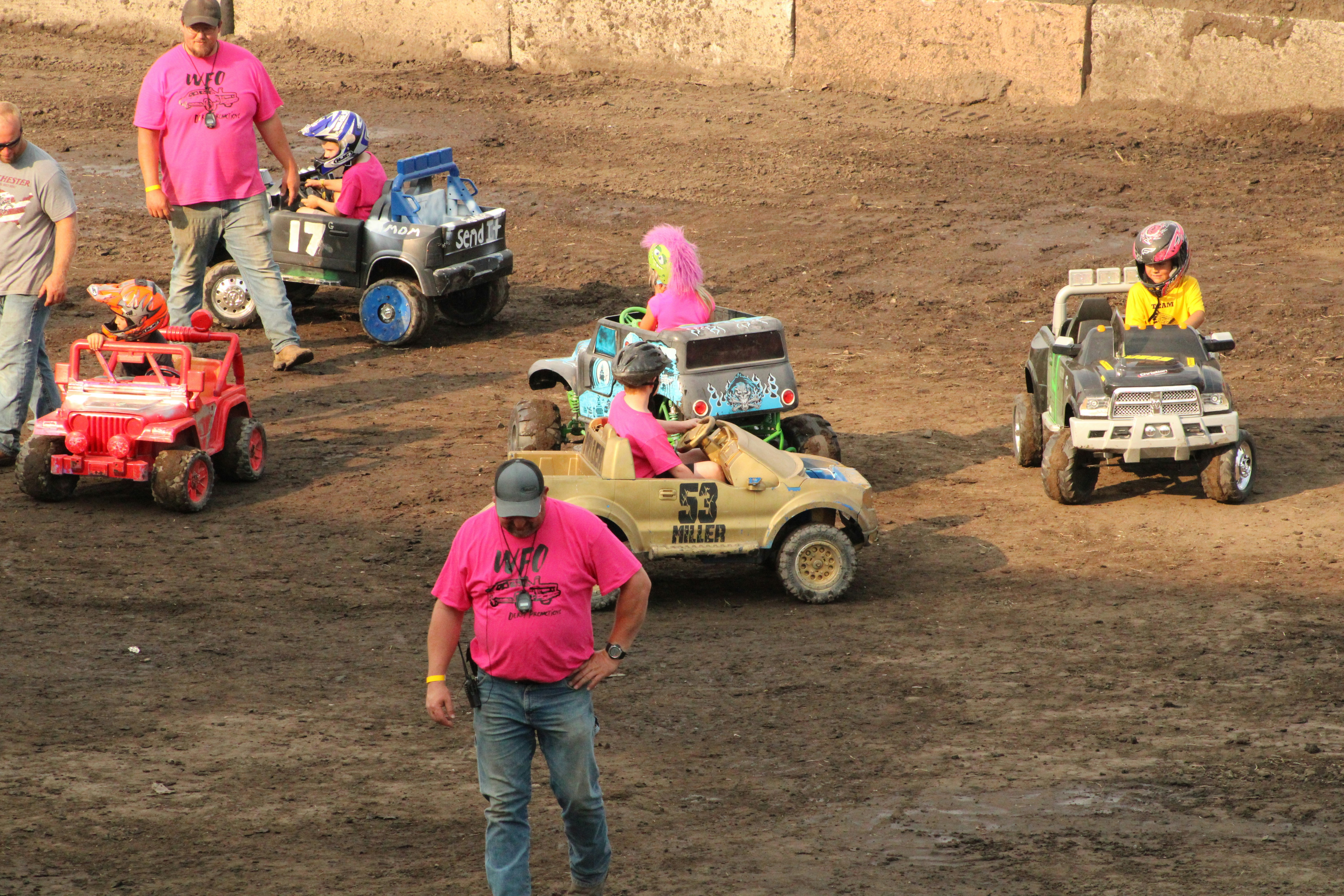 a group of people in pink shirts standing around a dirt field