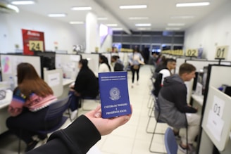 a person holding up a blue passport in an office