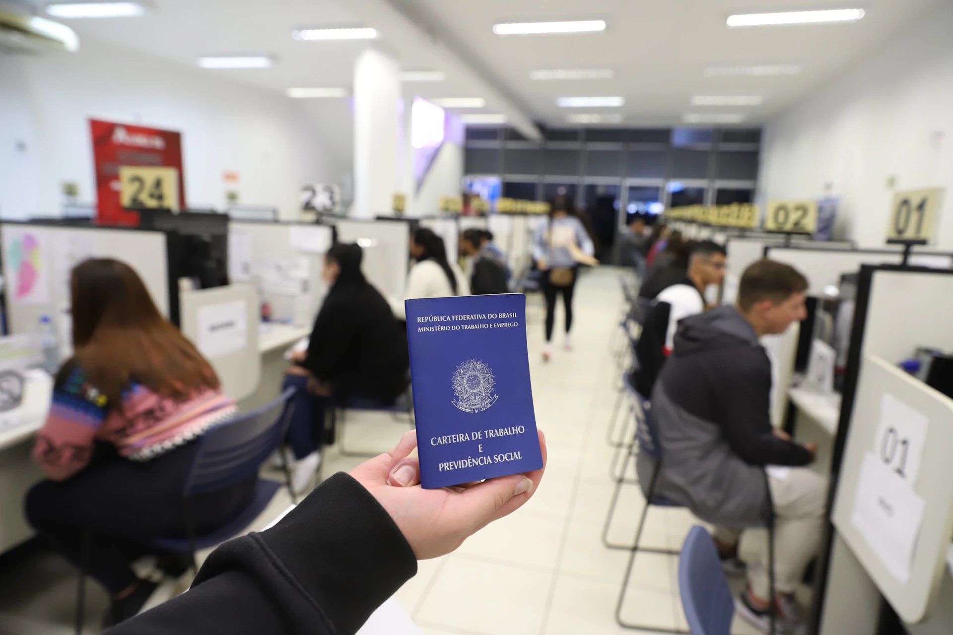 a person holding up a blue passport in an office