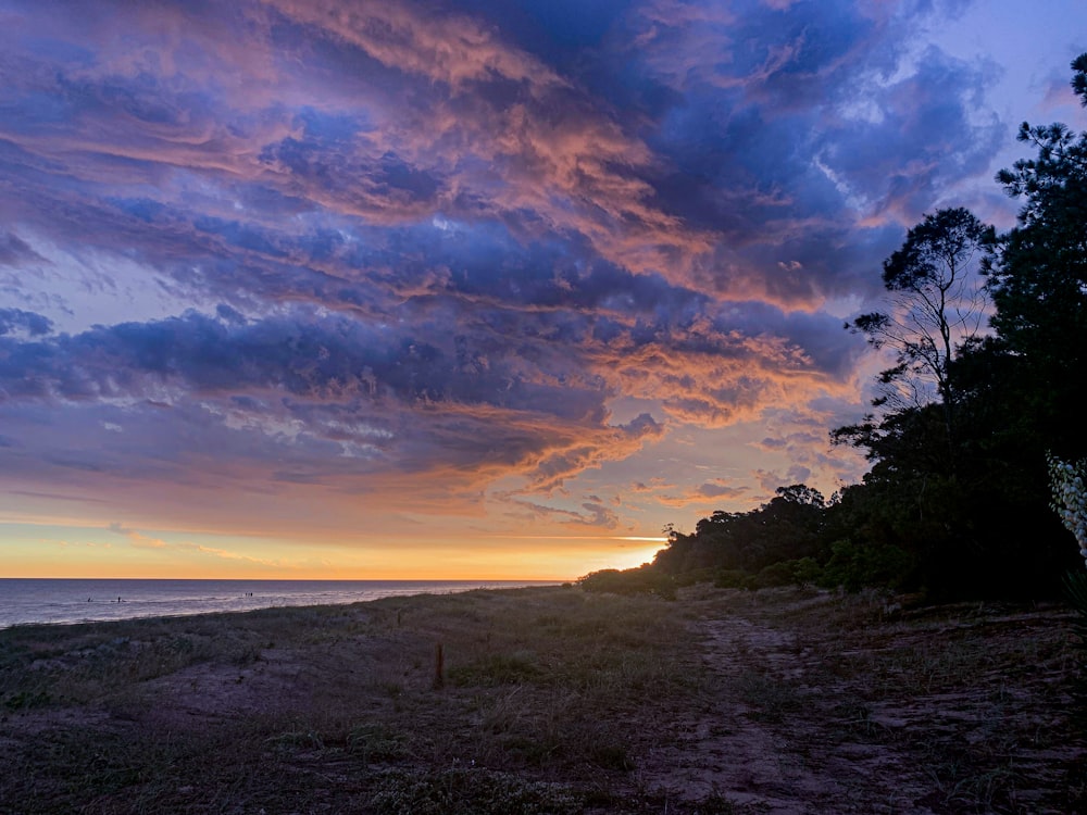 the sun is setting over the ocean with clouds in the sky