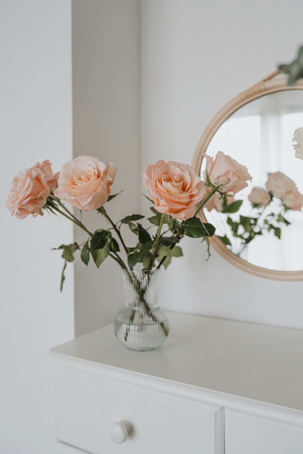a vase of flowers sitting on a dresser next to a mirror