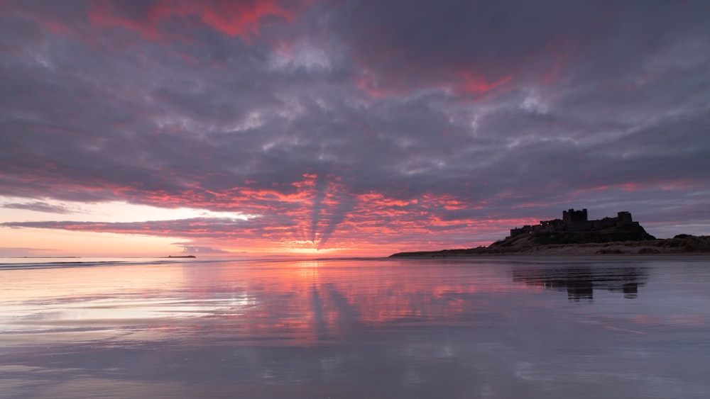 a sunset over a beach with a castle in the distance