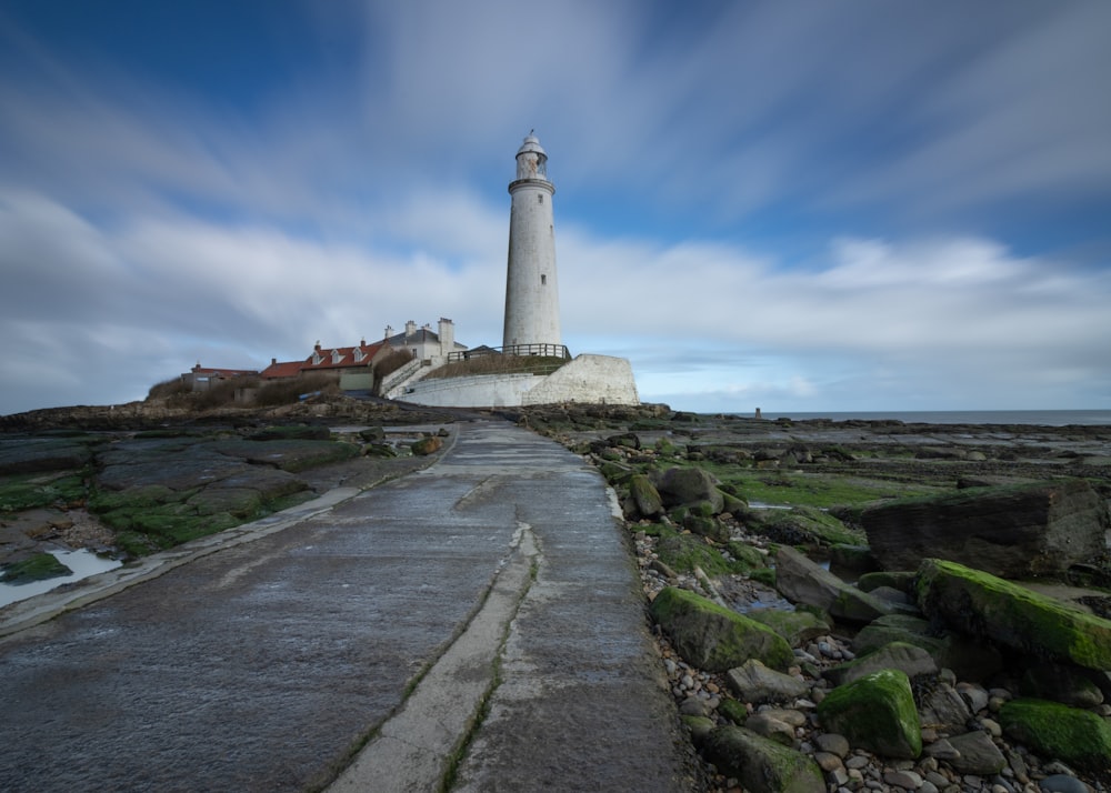 a white lighthouse sitting on top of a lush green field