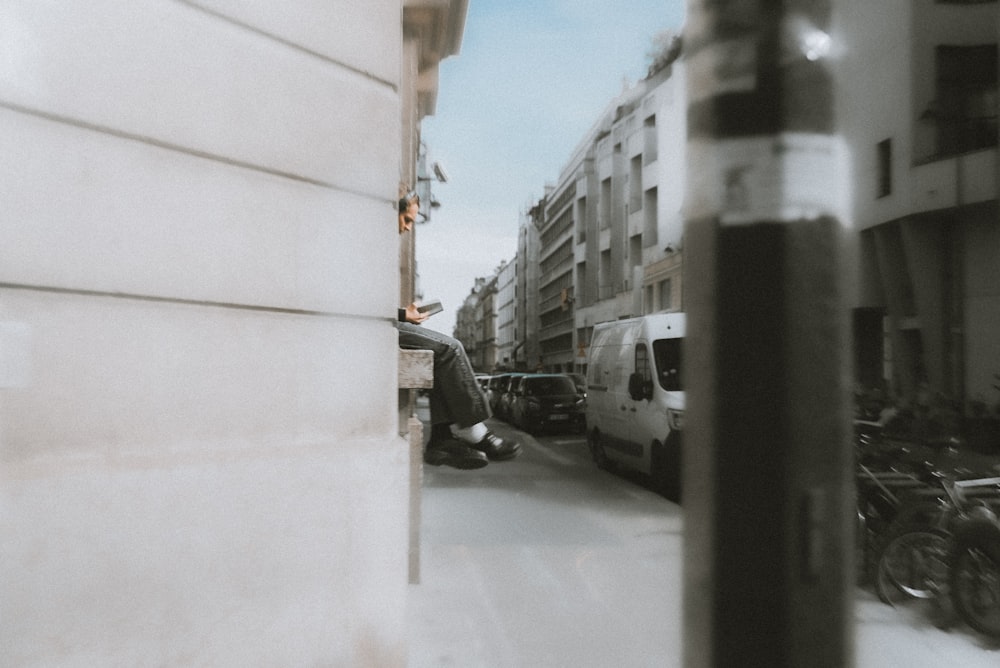 a person sitting on a ledge next to a building