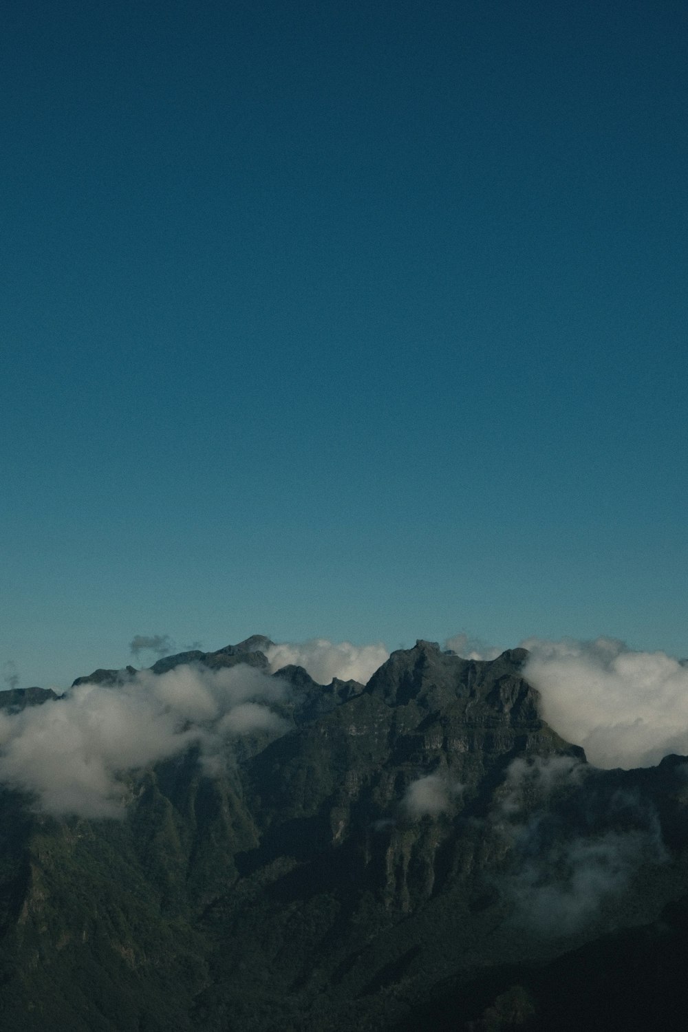 un avión volando sobre una montaña cubierta de nubes